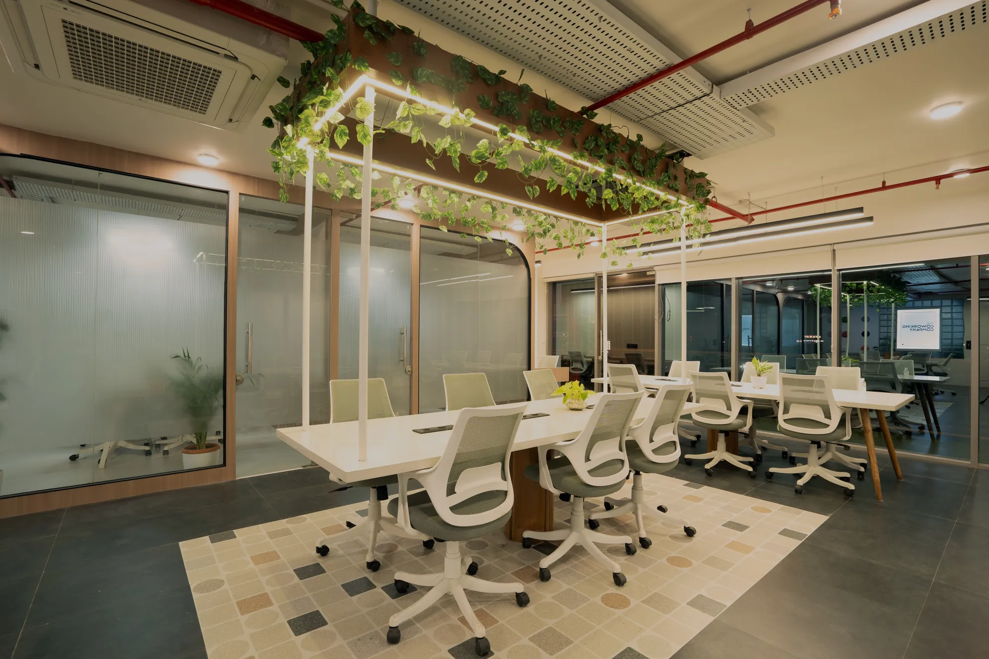 Open workspace with a suspended planter frame above long shared desks