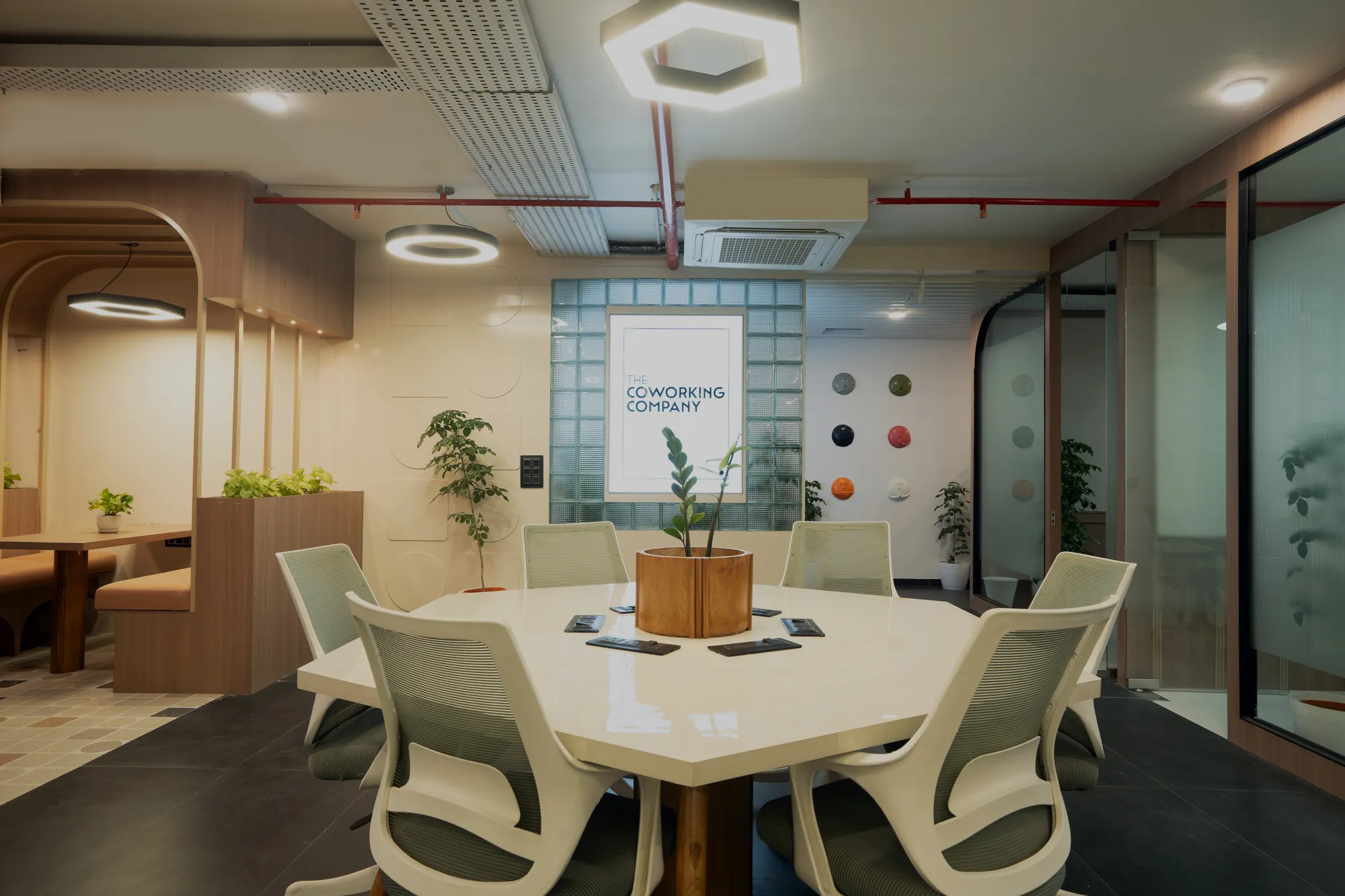 Meeting table beneath a ring light, framed by arched timber partitions and a glass-block wall