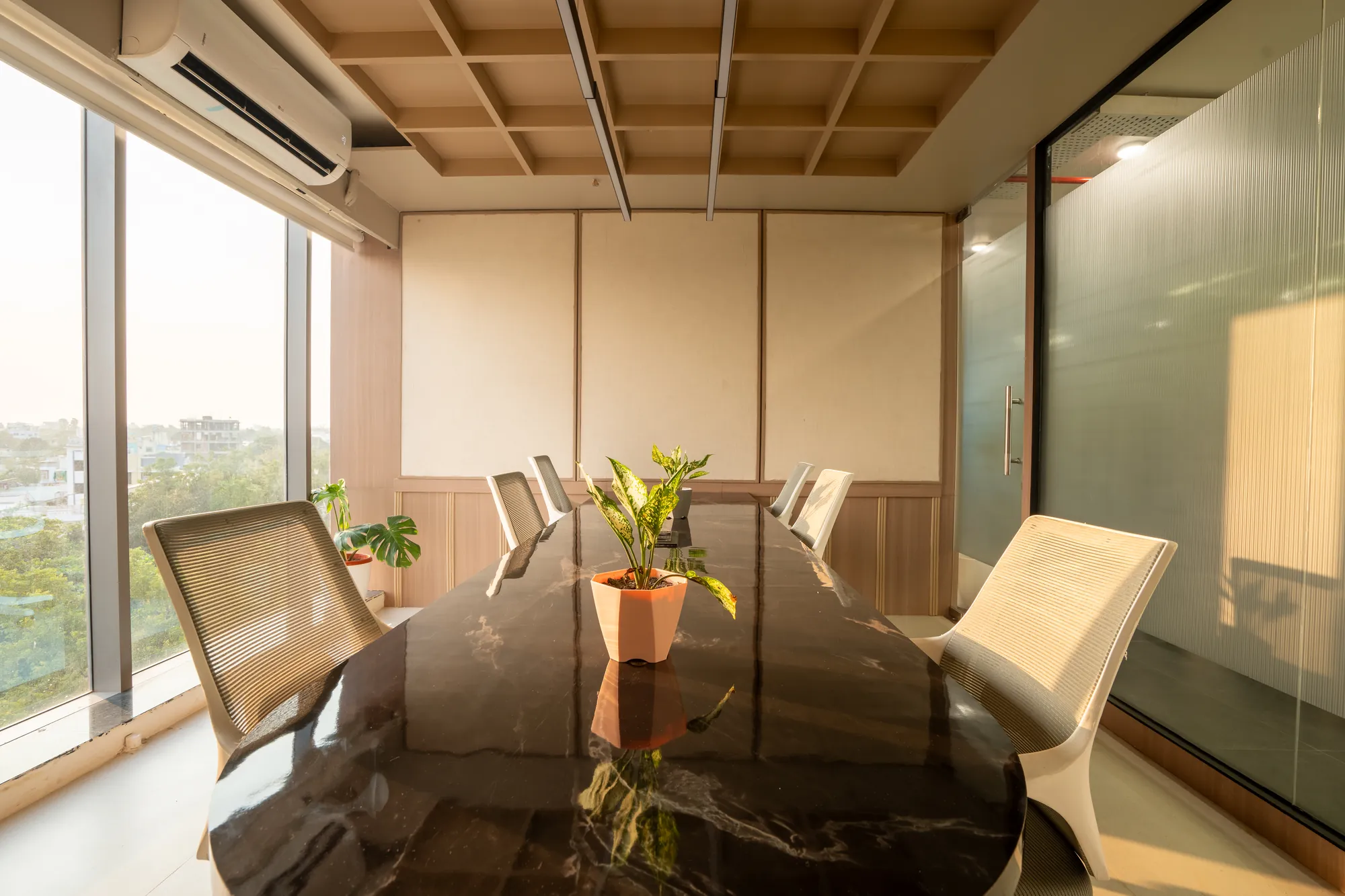 Meeting room with a dark stone table, coffered timber ceiling and city views