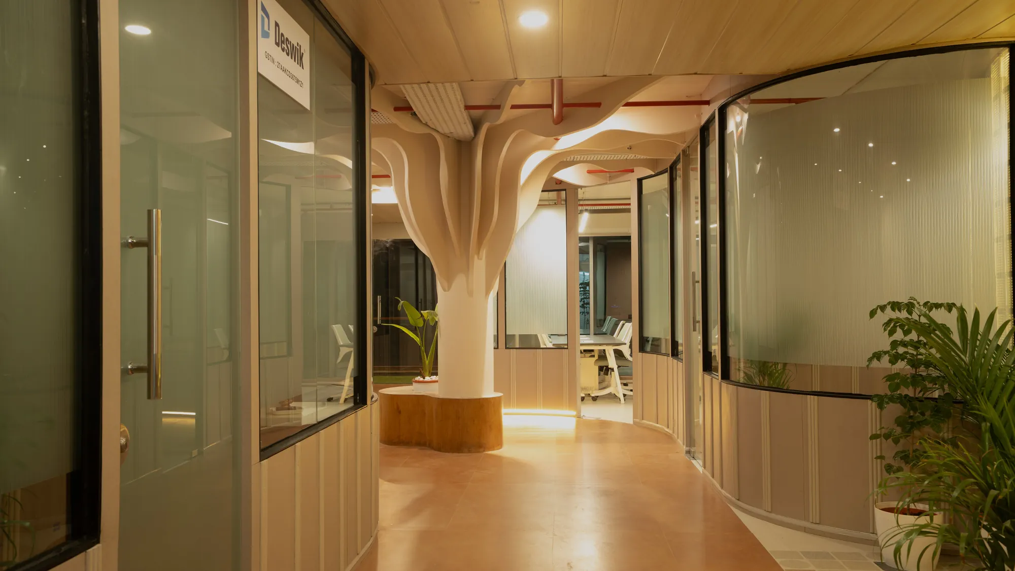 Sculptural white column branching into the ceiling between glass-fronted cabins