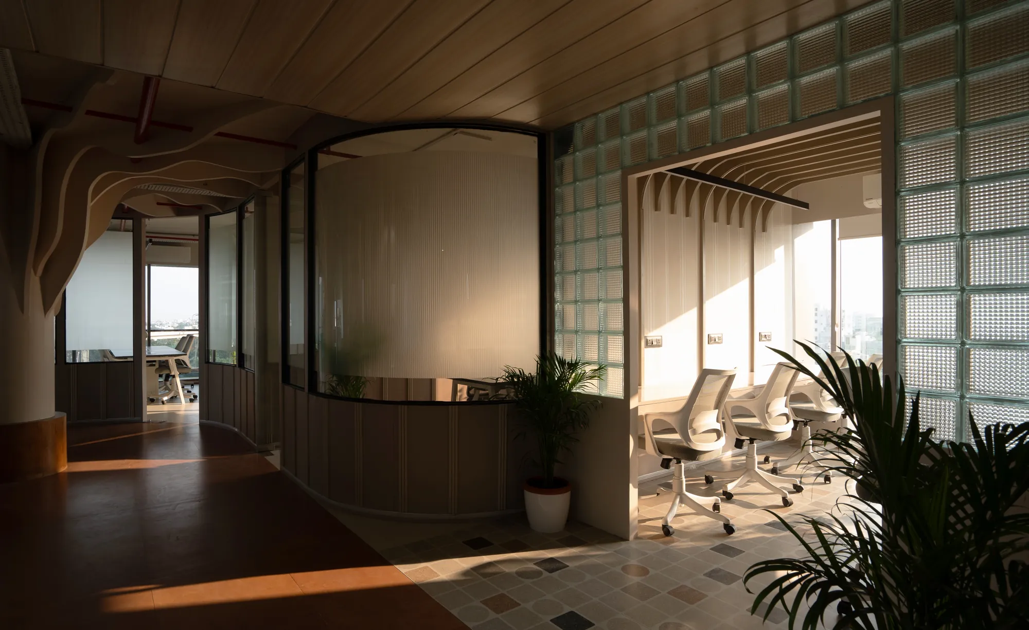 Glass-block partition and curved timber walls catching low sunlight
