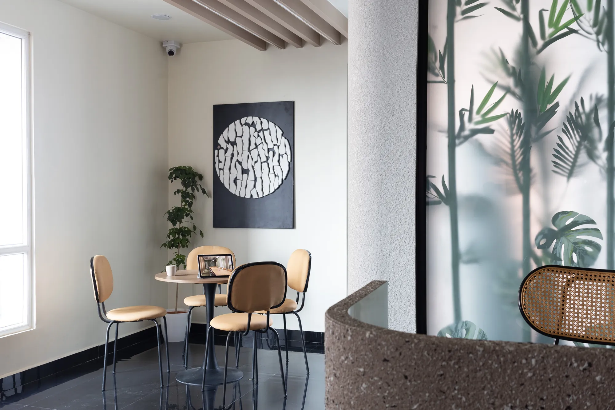 Café corner with cane chairs beside a frosted botanical glass screen