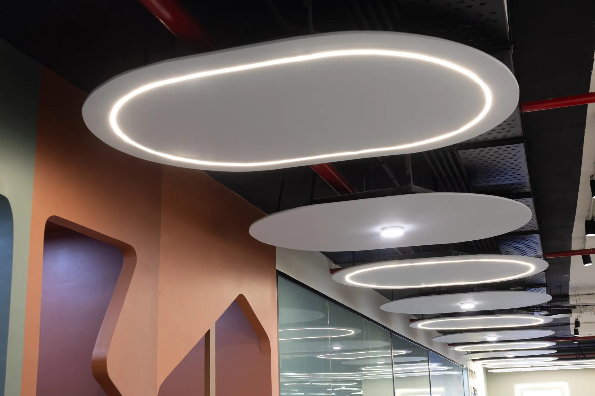 Sculpted terracotta booth openings under floating oval light fixtures
