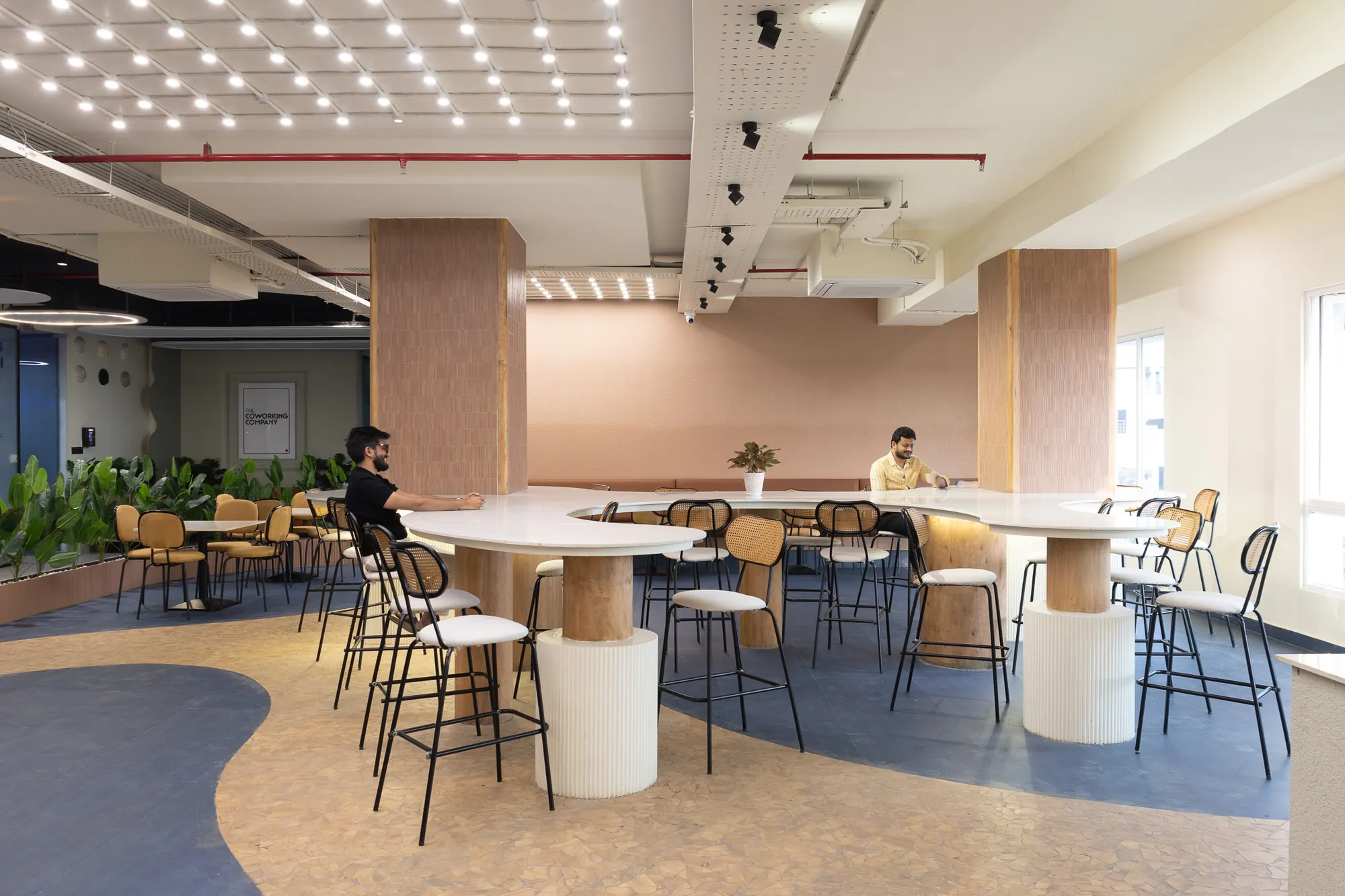 Café and breakout area with curved counters, mustard chairs and a blue-and-sand floor