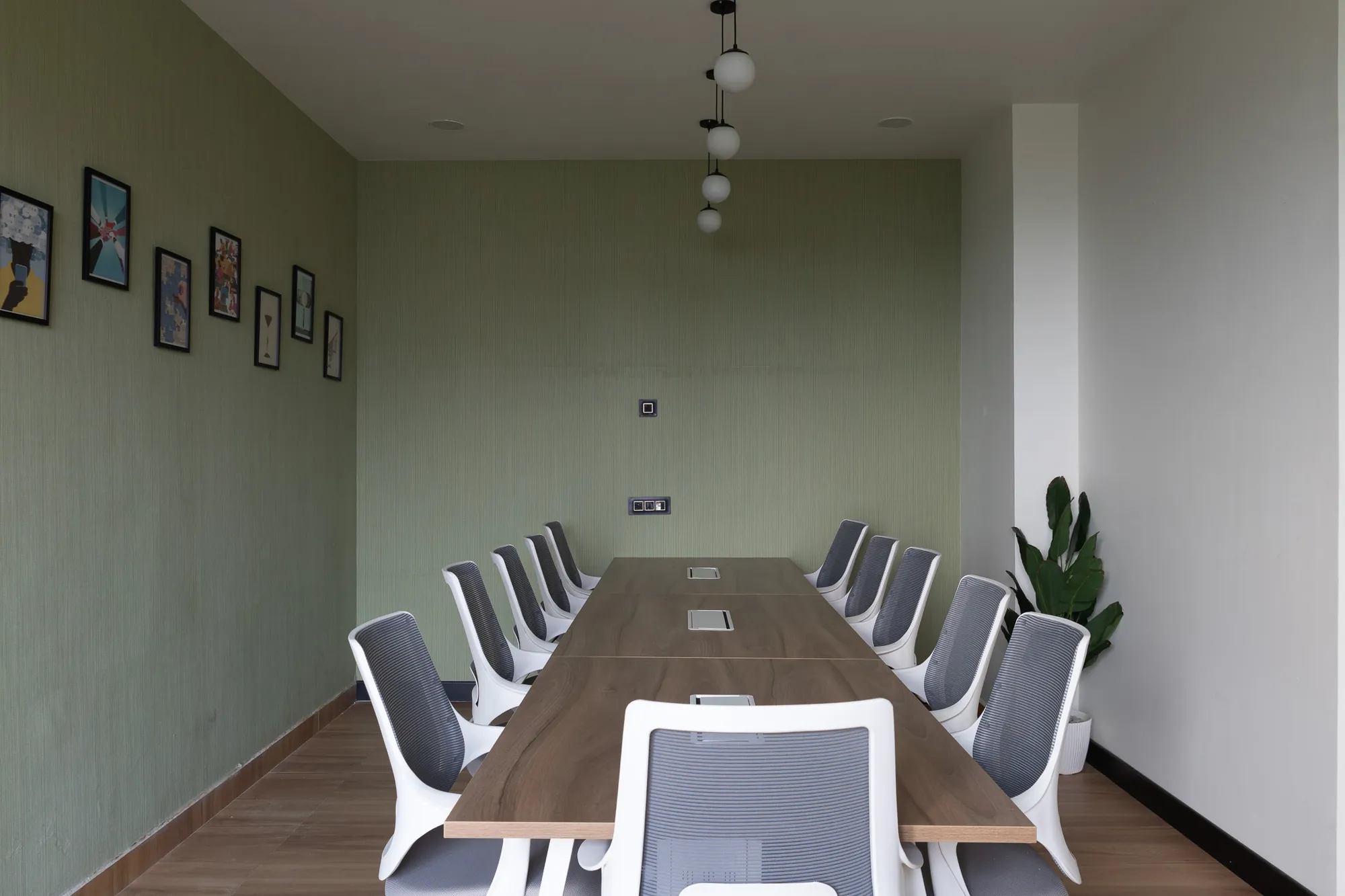 Sage-walled boardroom with a long walnut table
