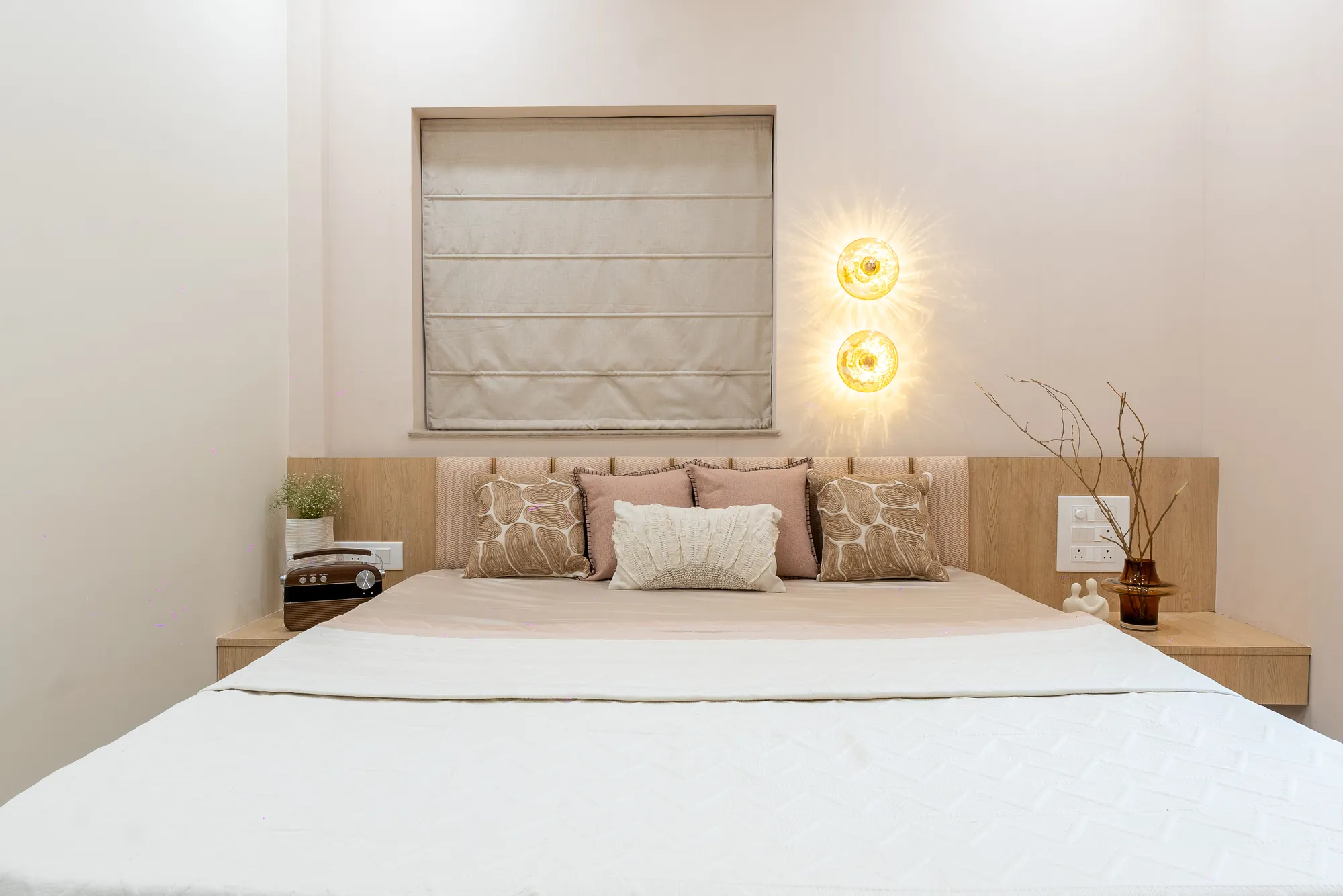 Guest bedroom in acacia with a panelled headboard and glowing wall sconces