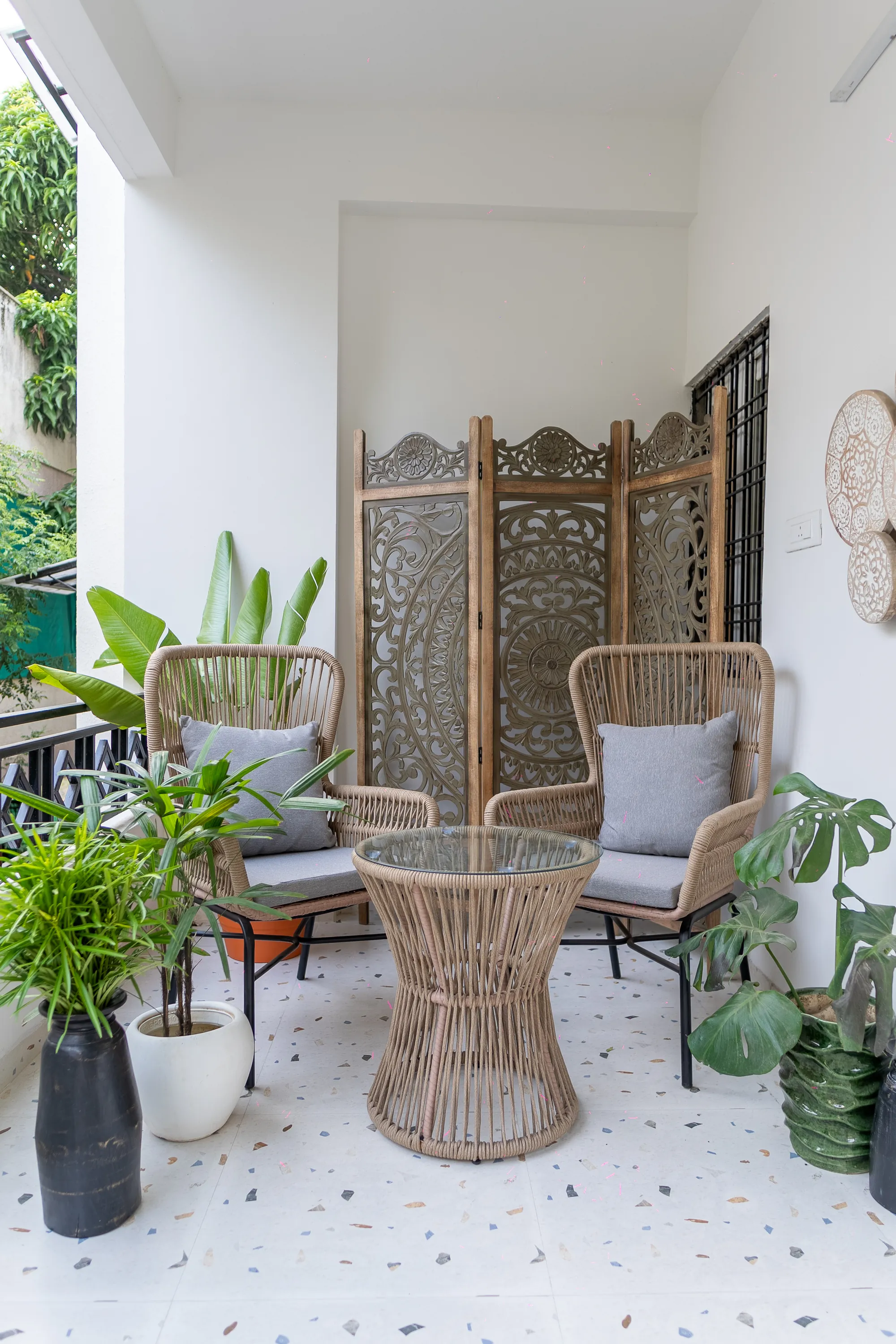 Balcony seating with cane chairs, planters and a carved screen