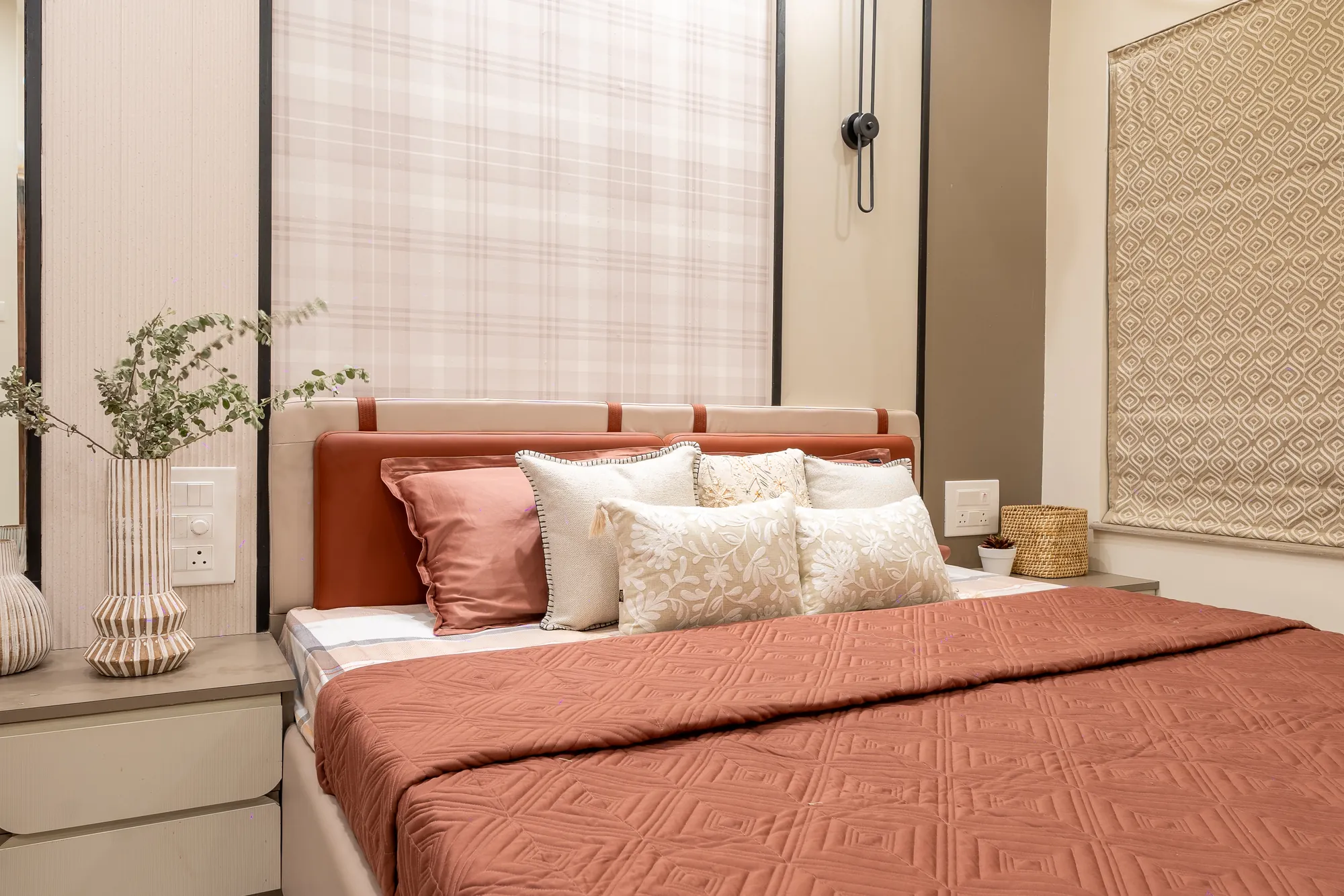 Bedroom with a terracotta bedspread, upholstered terracotta headboard and checked wall panel