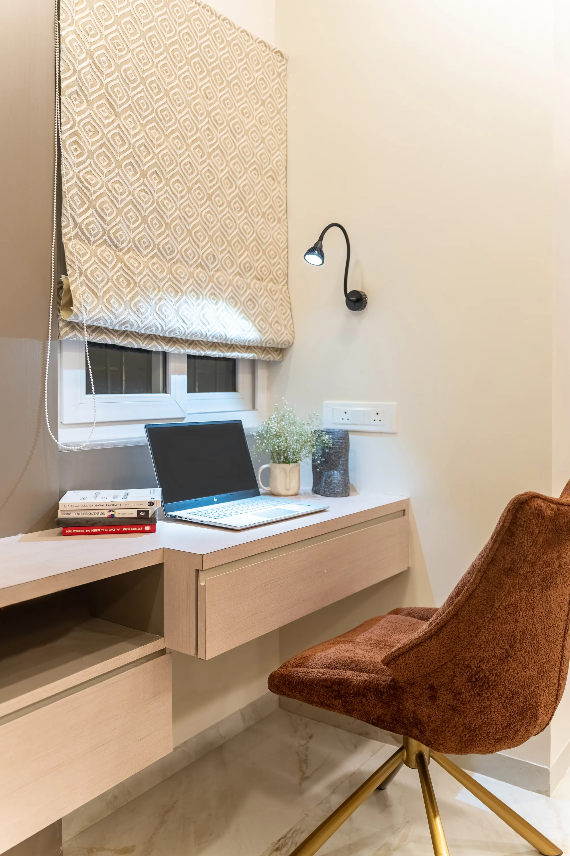 Study nook with a floating desk and a rust velvet chair beside the window