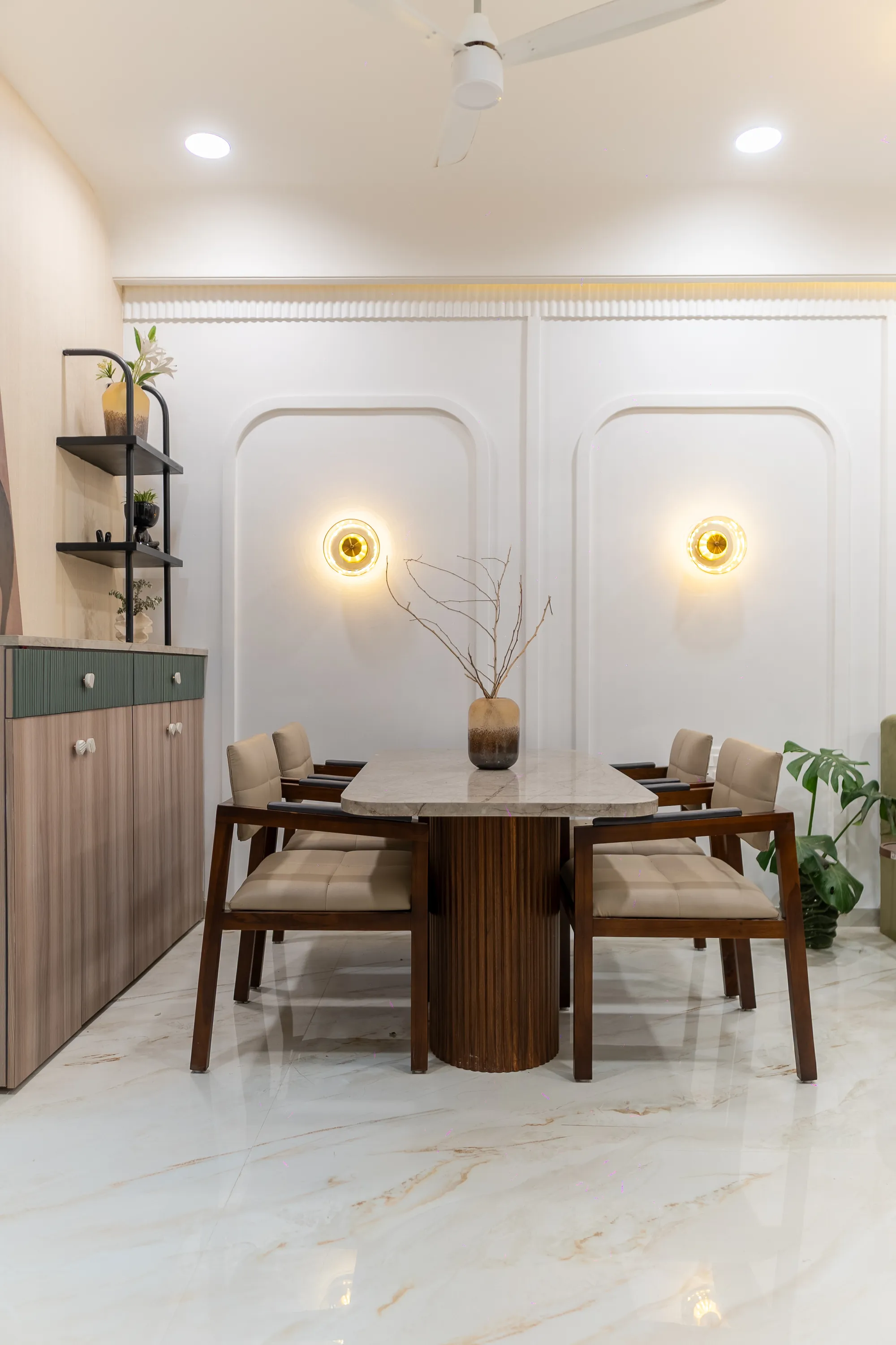Dining area with wooden chairs, a curved arched wall panel and a sage-green sideboard