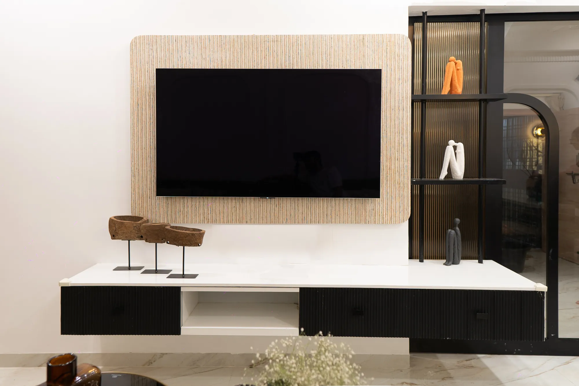 Television wall with a textured surround, a black fluted console and display shelving