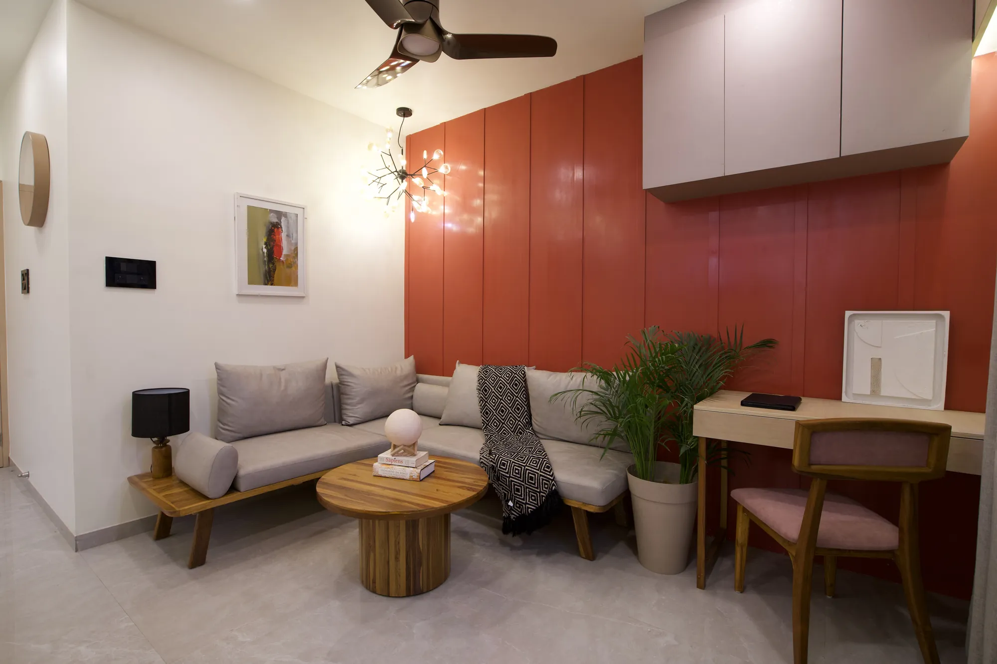 Living area with a deep coral panelled wall, grey sofa and round timber coffee table