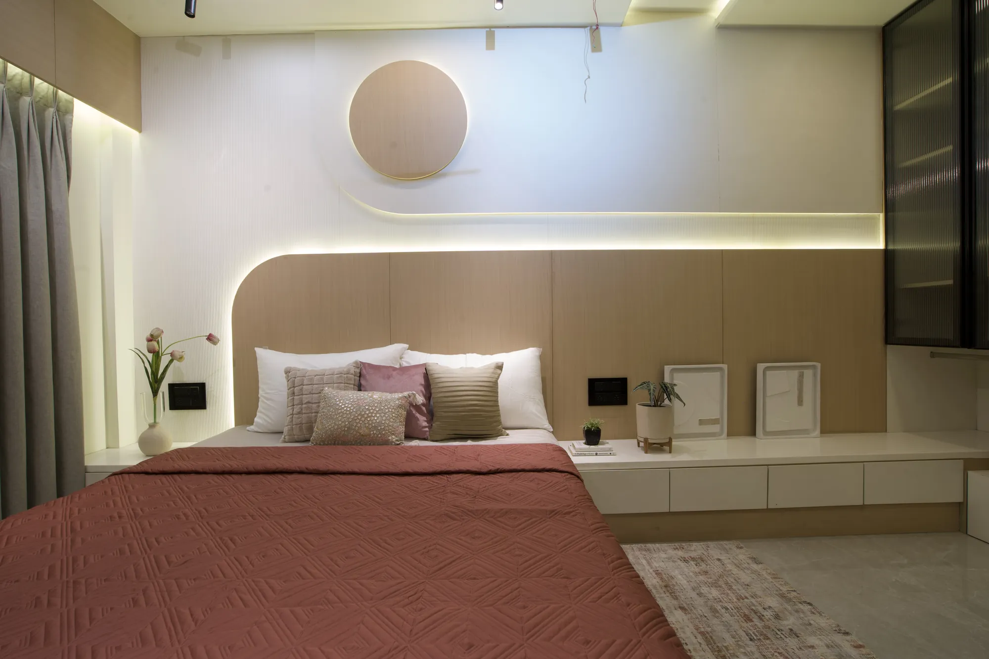 Bedroom with a curved wood-panelled headboard wall and a coral bedspread