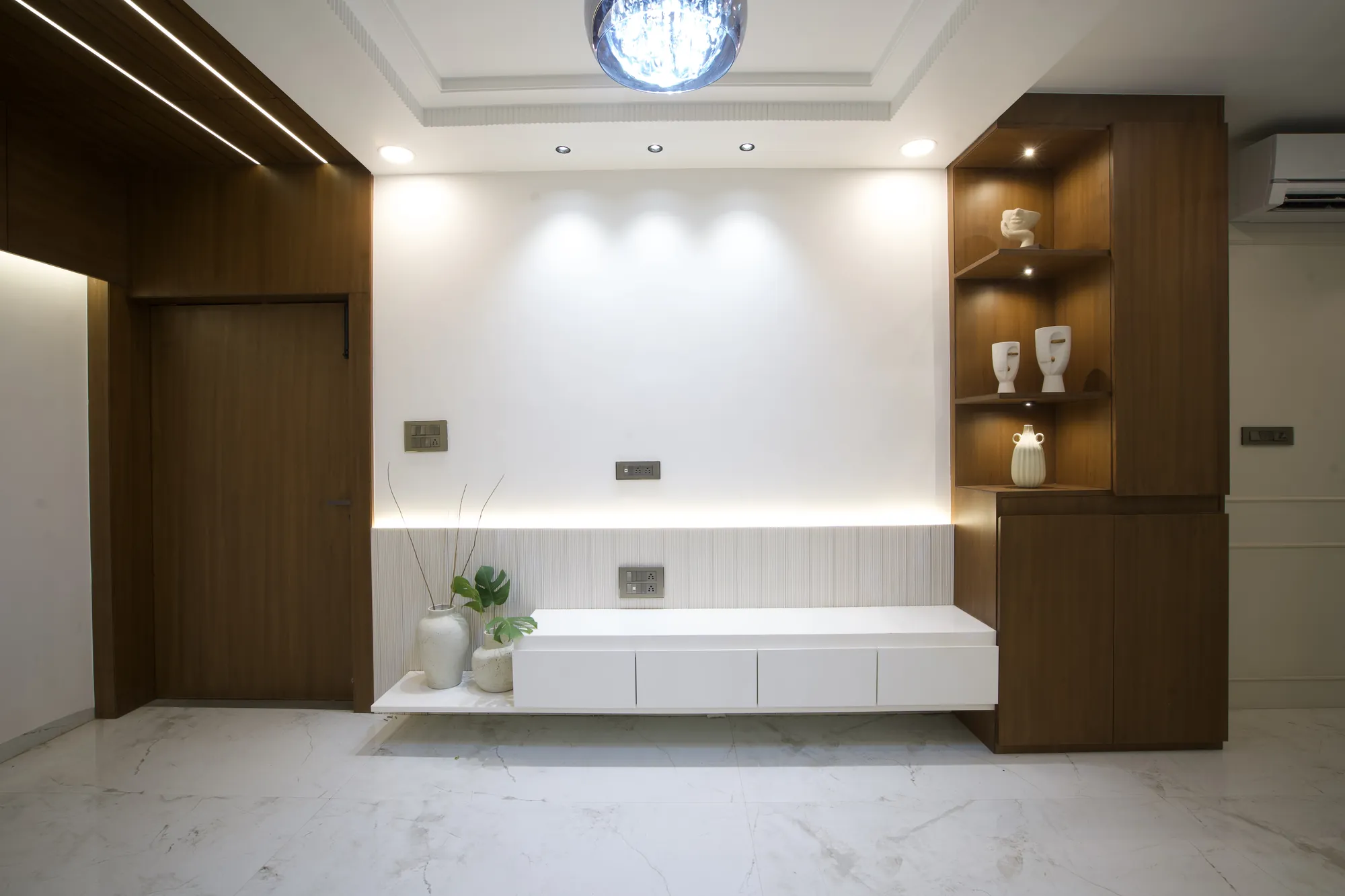 Television wall with walnut cladding, lit corner shelving and a floating console