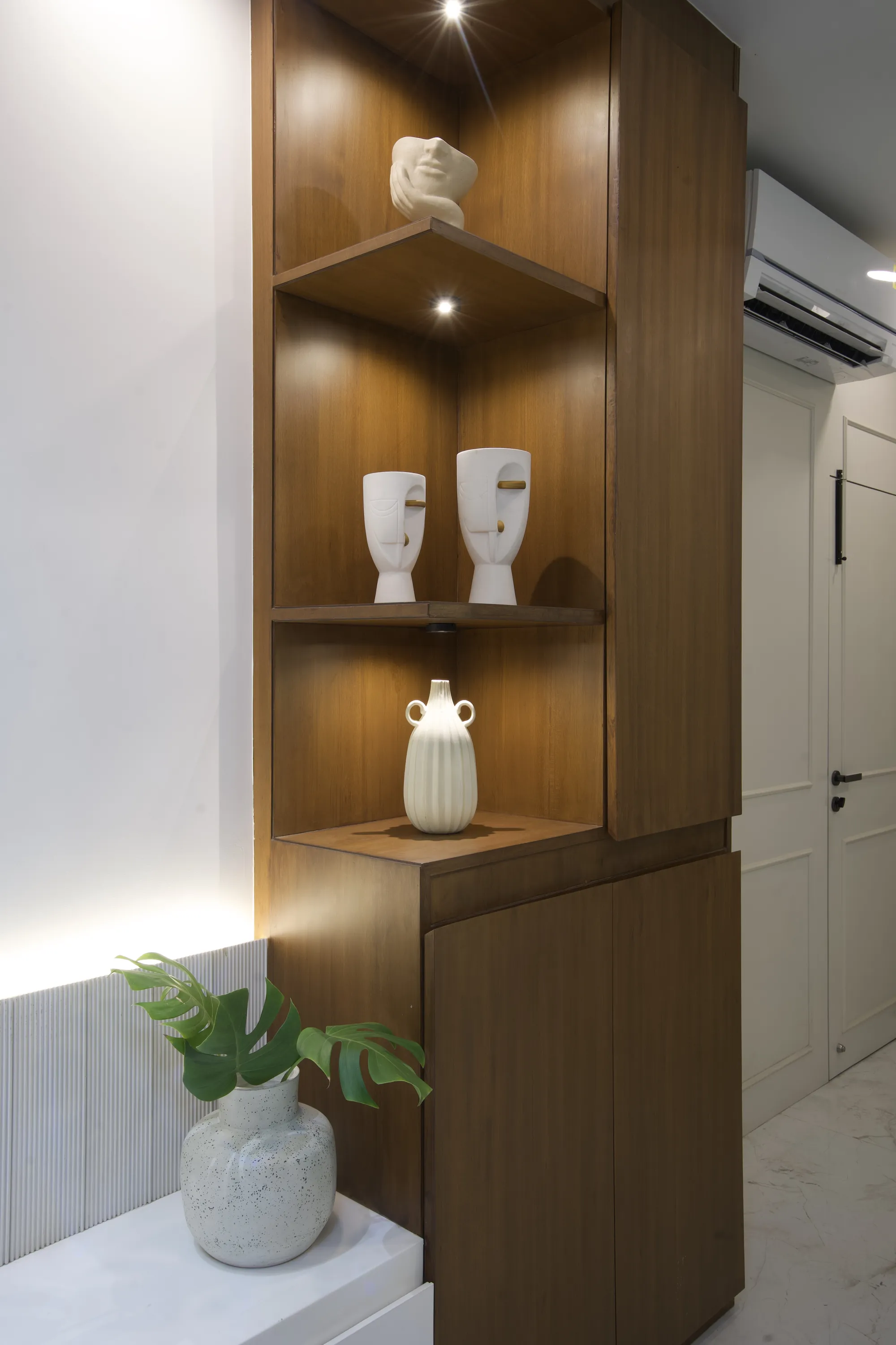 Detail of lit walnut corner shelving with ceramic vases