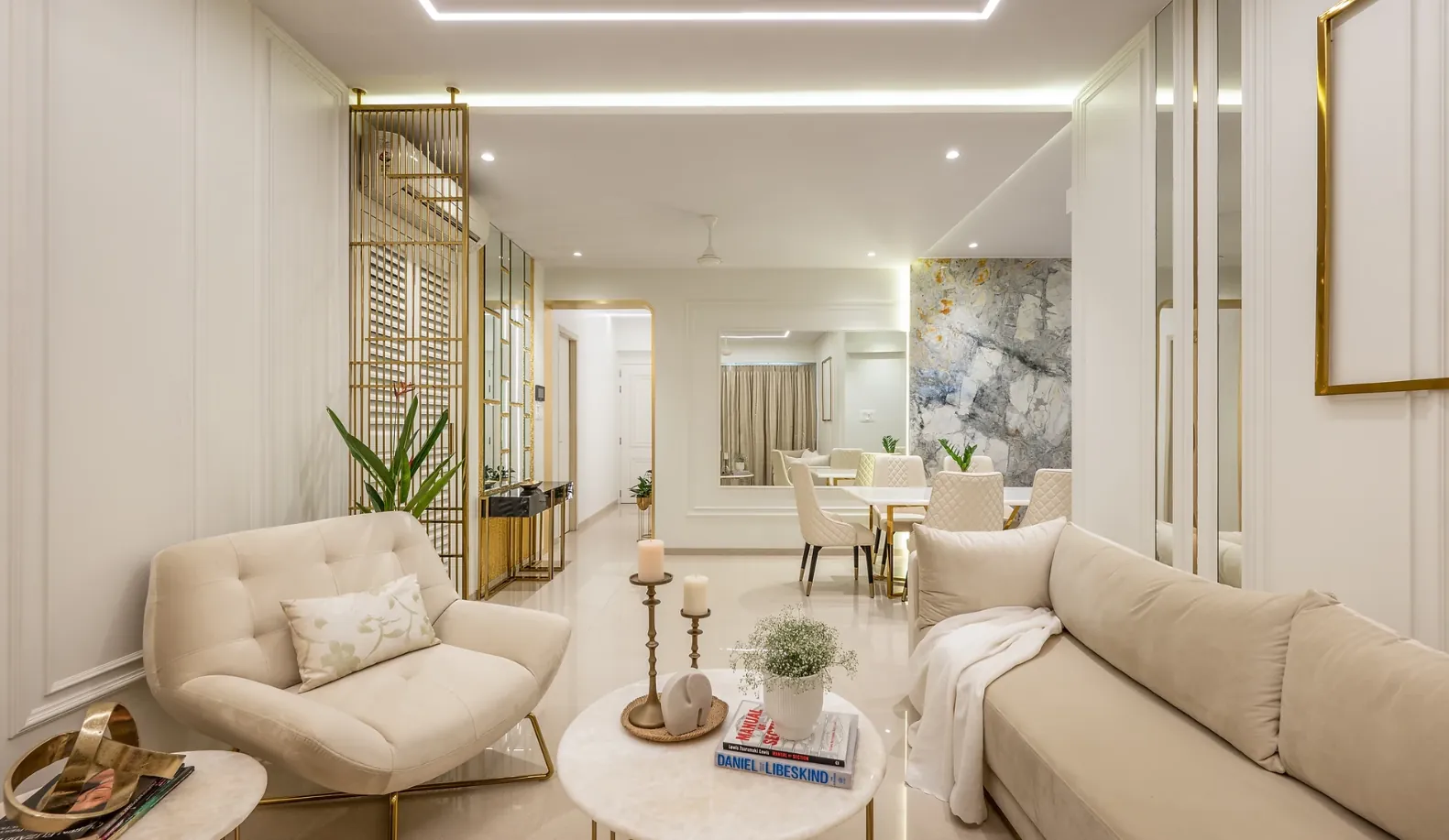 Ivory living room with tufted armchairs, mirrored wall strips and a stone feature wall beyond the dining table