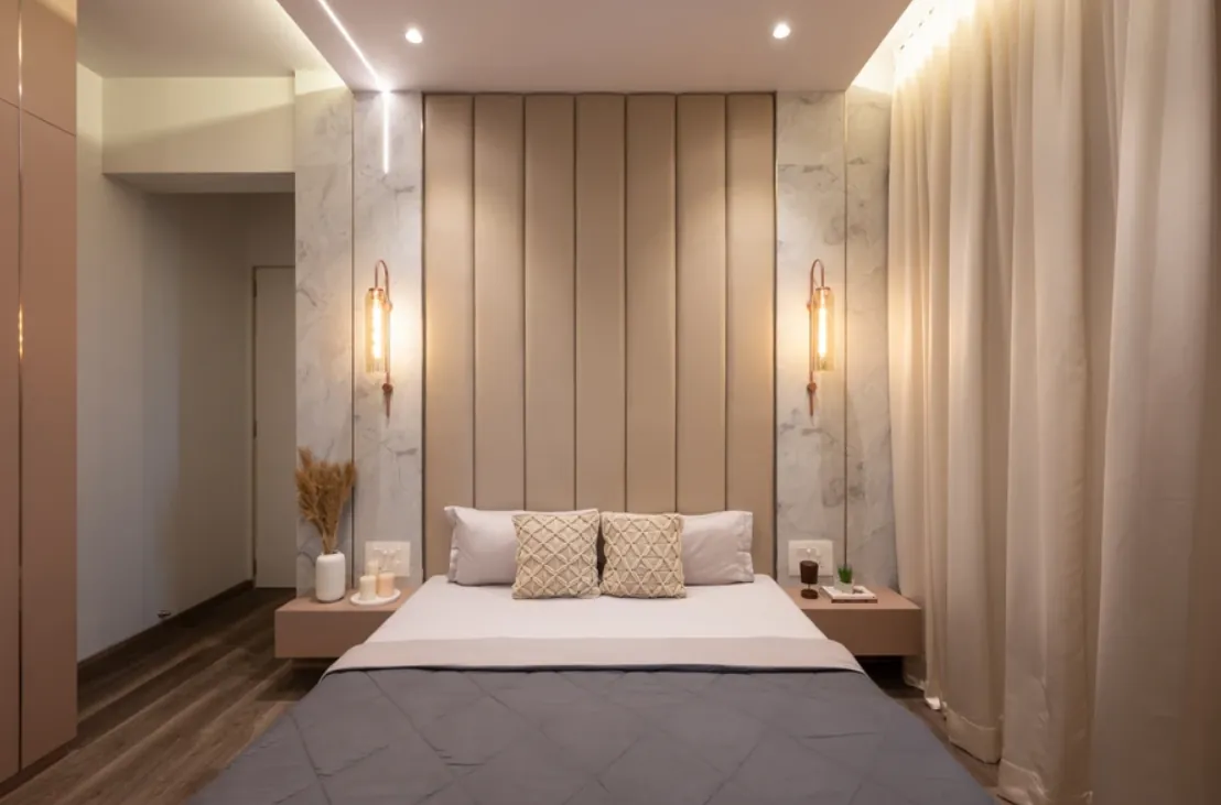 Bedroom with a beige panelled headboard, stone accent and brass wall lights